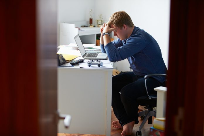 Teenage Boy Studying In Bedroom Using Laptop