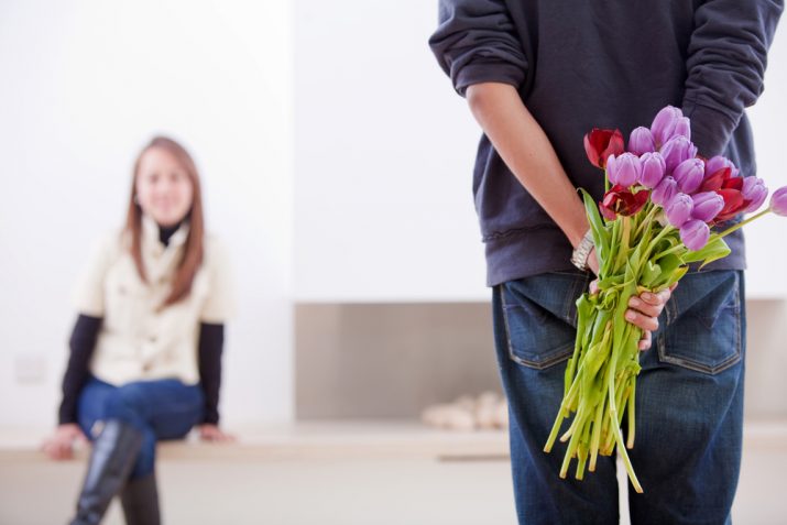 A men hiding a bunch of flowers for her girlfriend