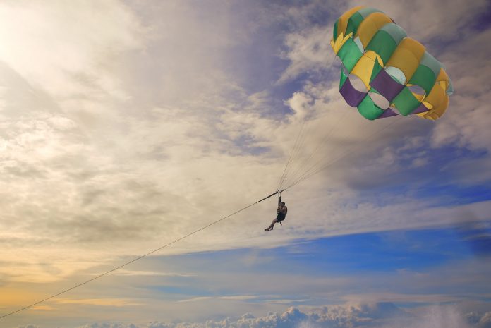 Couple-Parasialing-With-Colorful-Parachute-And-Dramatic-Sky-min