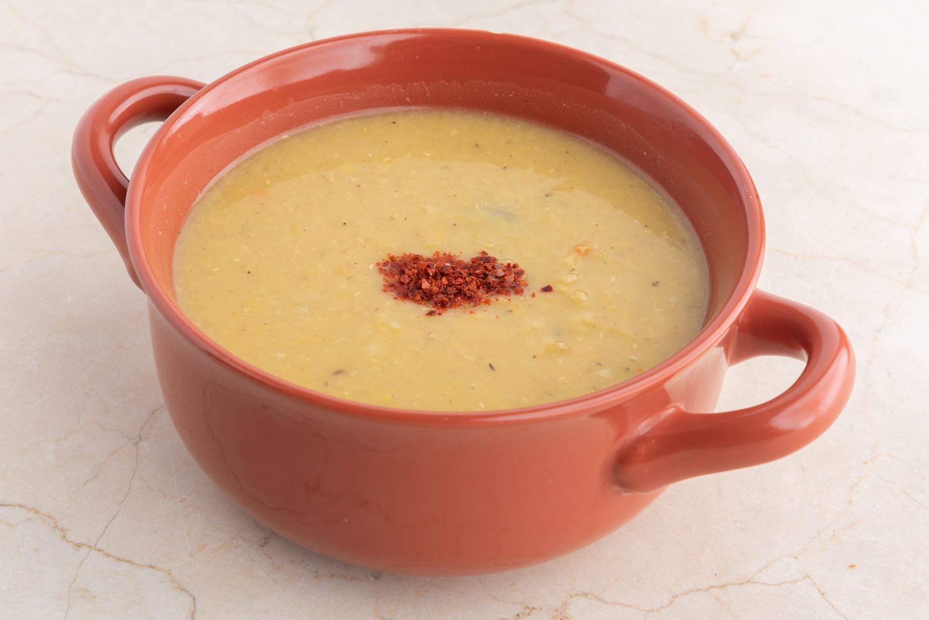 Delicious homemade lentil soup in a terra cotta bowl, perfect for a comforting meal.