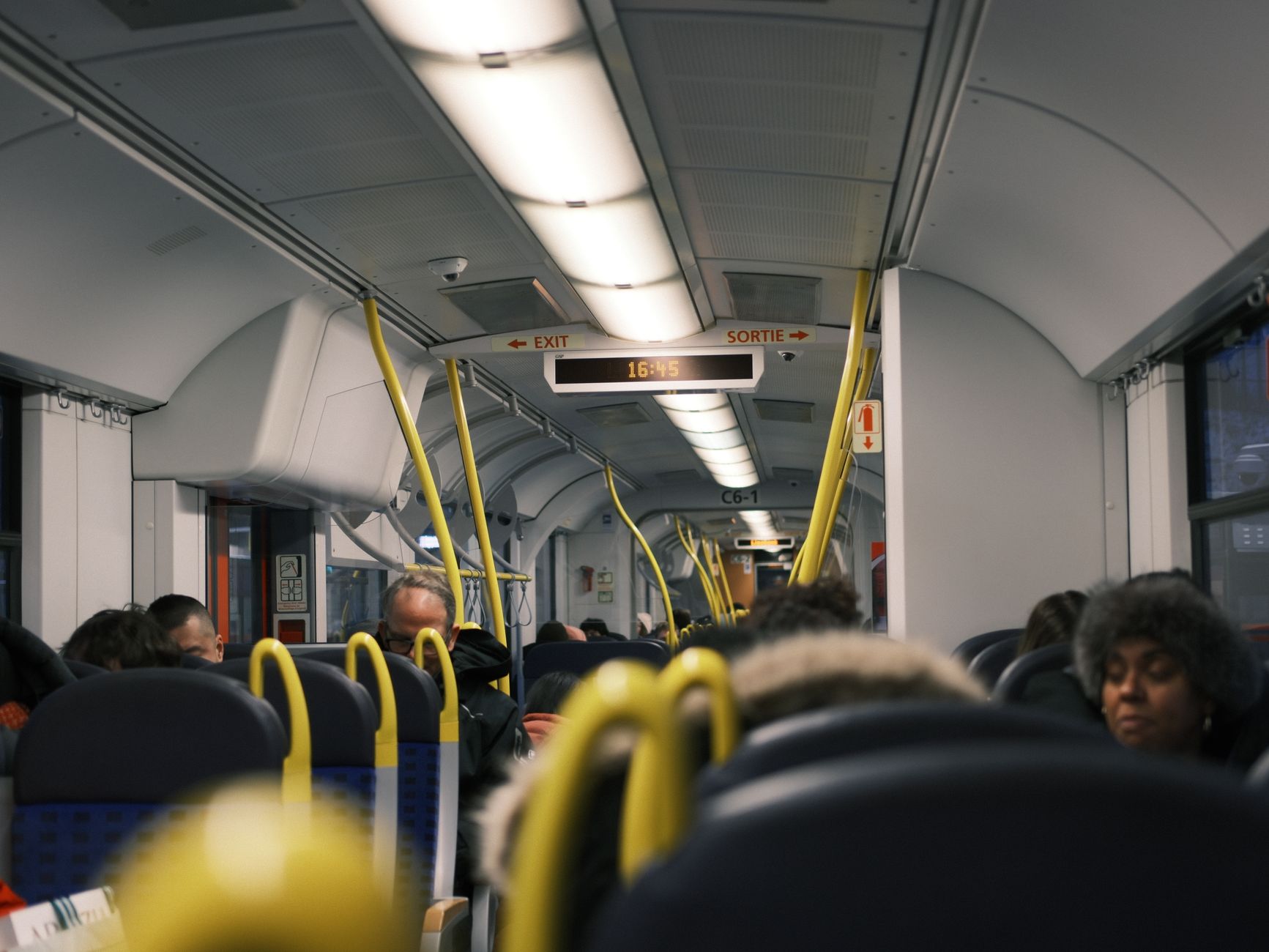 Passengers commuting inside a modern public train during the day.
