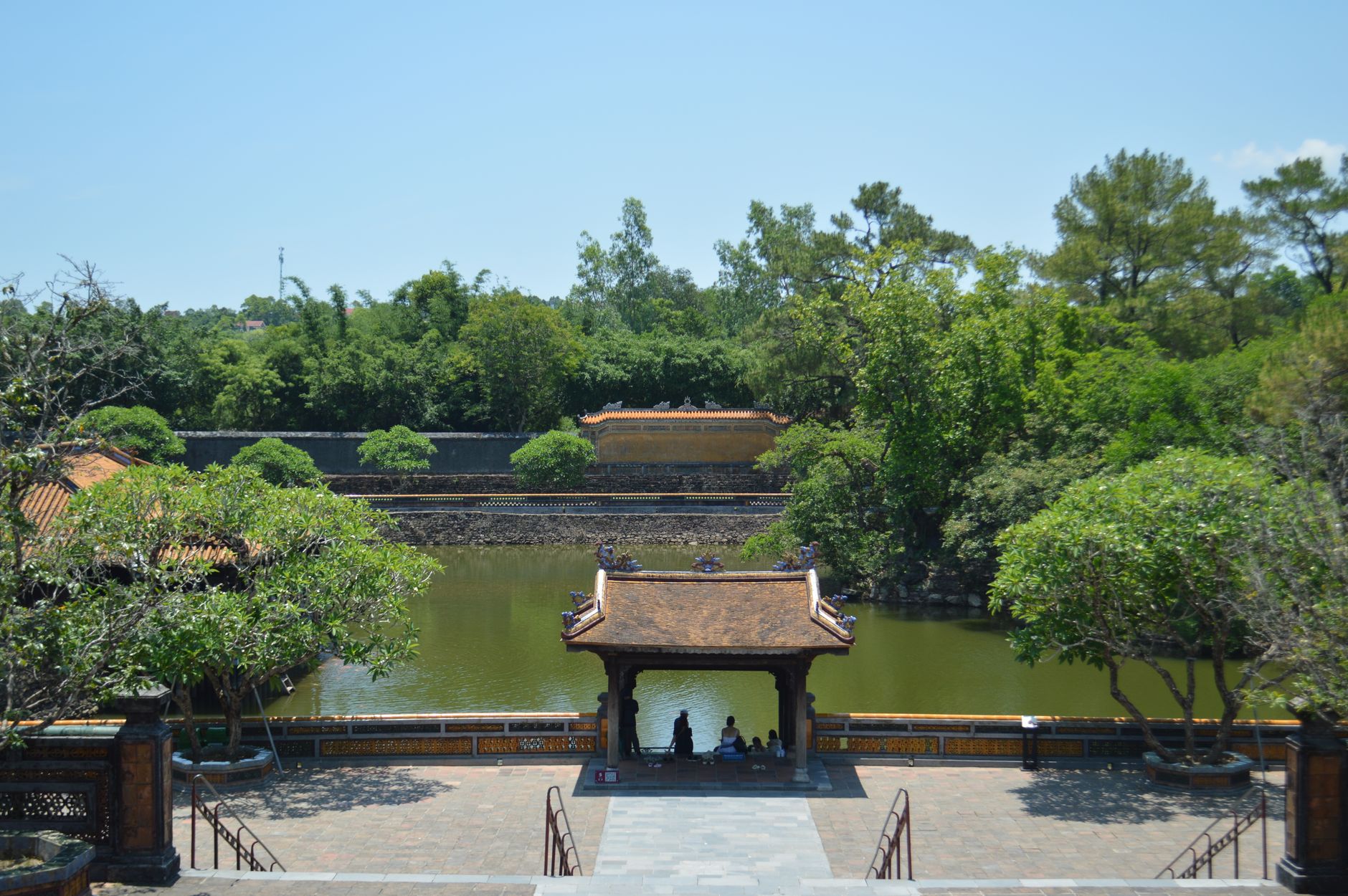 Serene temple garden with a tranquil pond surrounded by lush greenery.