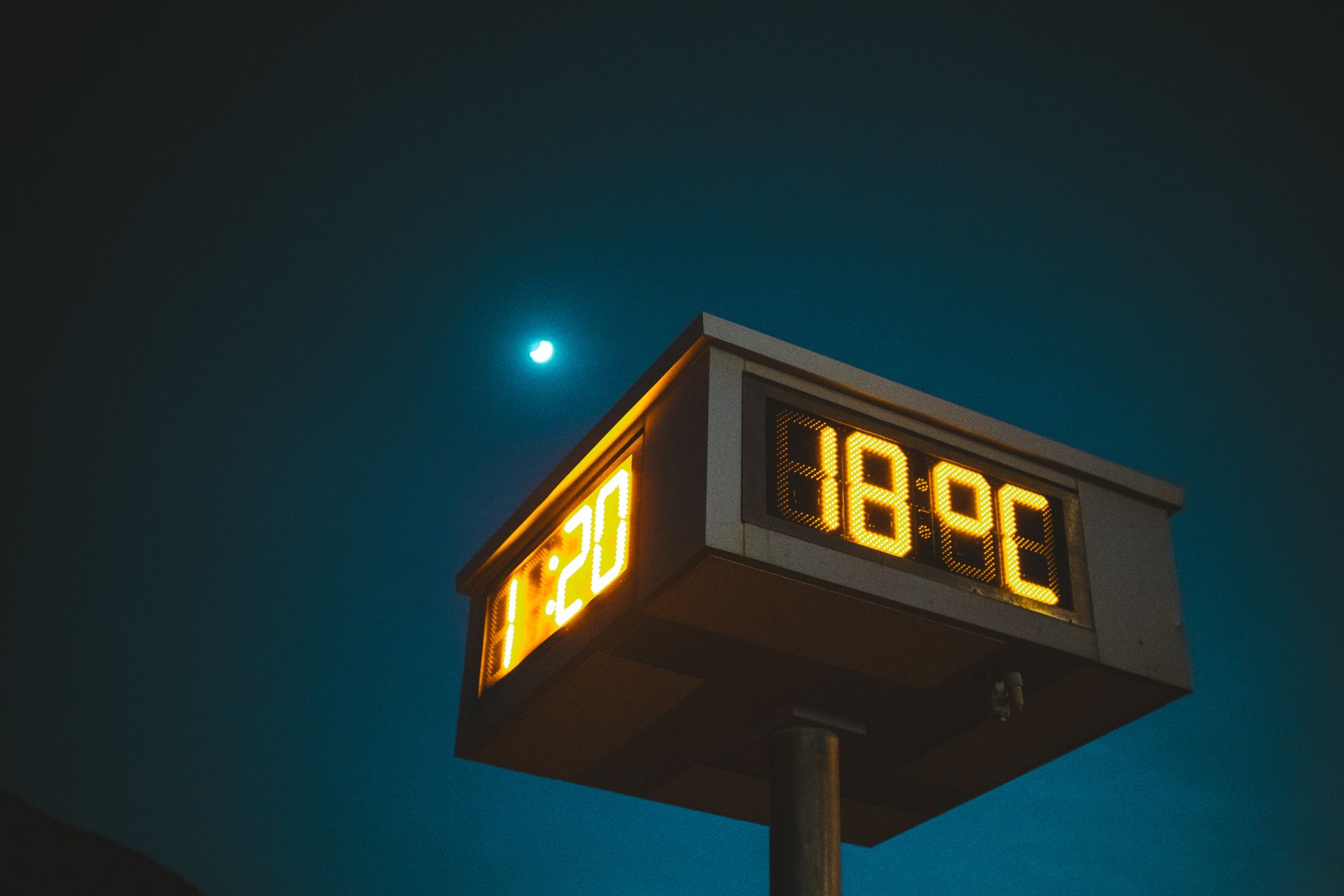 A digital clock shows time and temperature against a night sky with a visible moon.