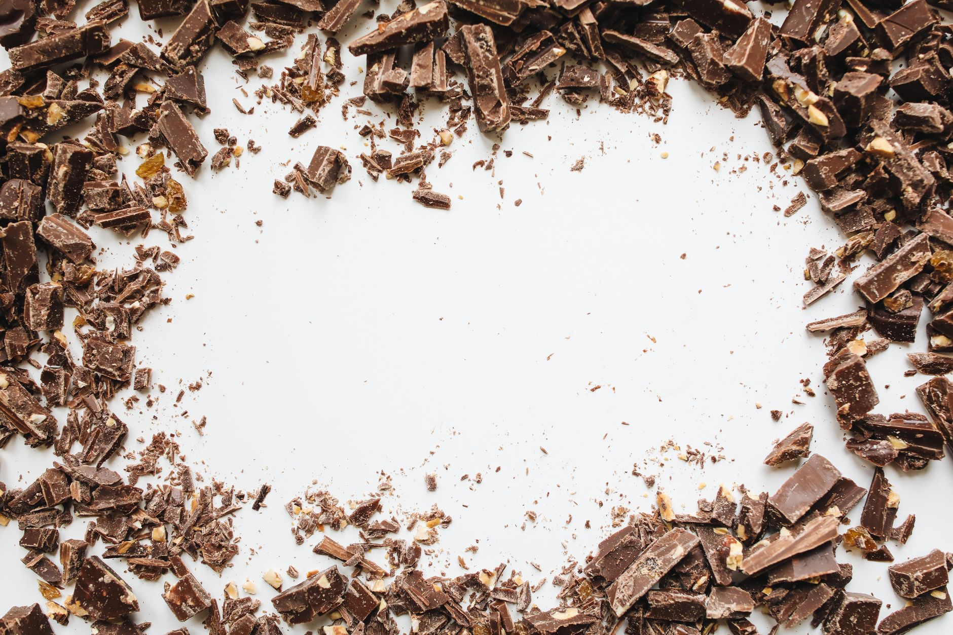 Scattered chocolate chunks on a white surface creating an indulgent food texture.