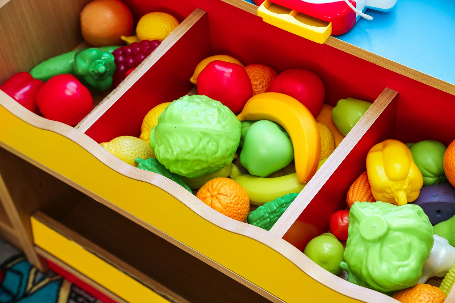 A vibrant assortment of toy fruits and vegetables in a play kitchen setting.