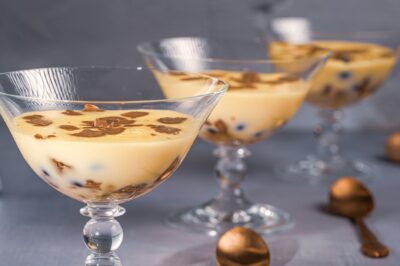 Close-up of three elegant desserts in glass dishes with chocolate shavings and berries.