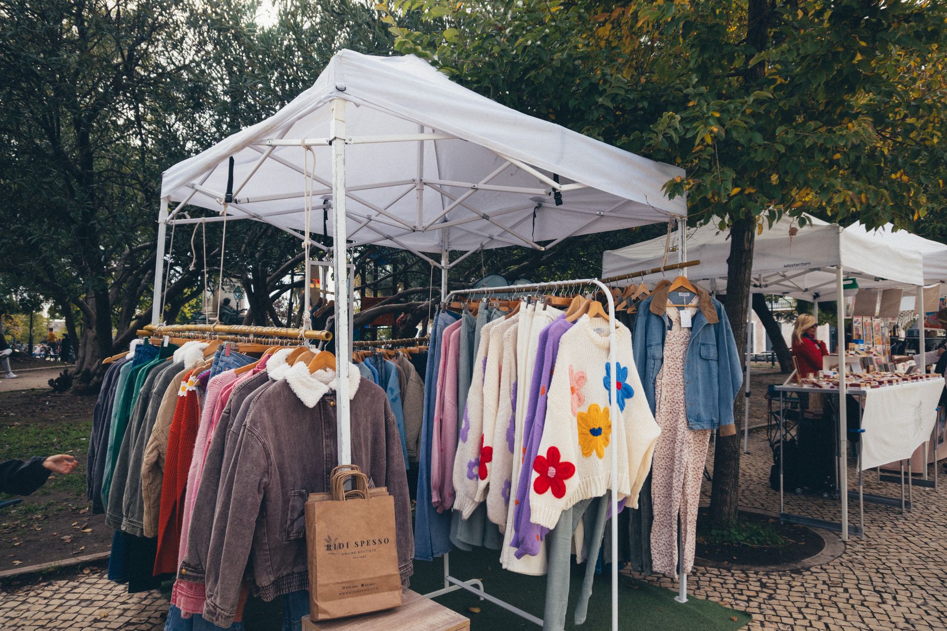 Vibrant outdoor market showcasing colorful clothes on hangers under a canopy.