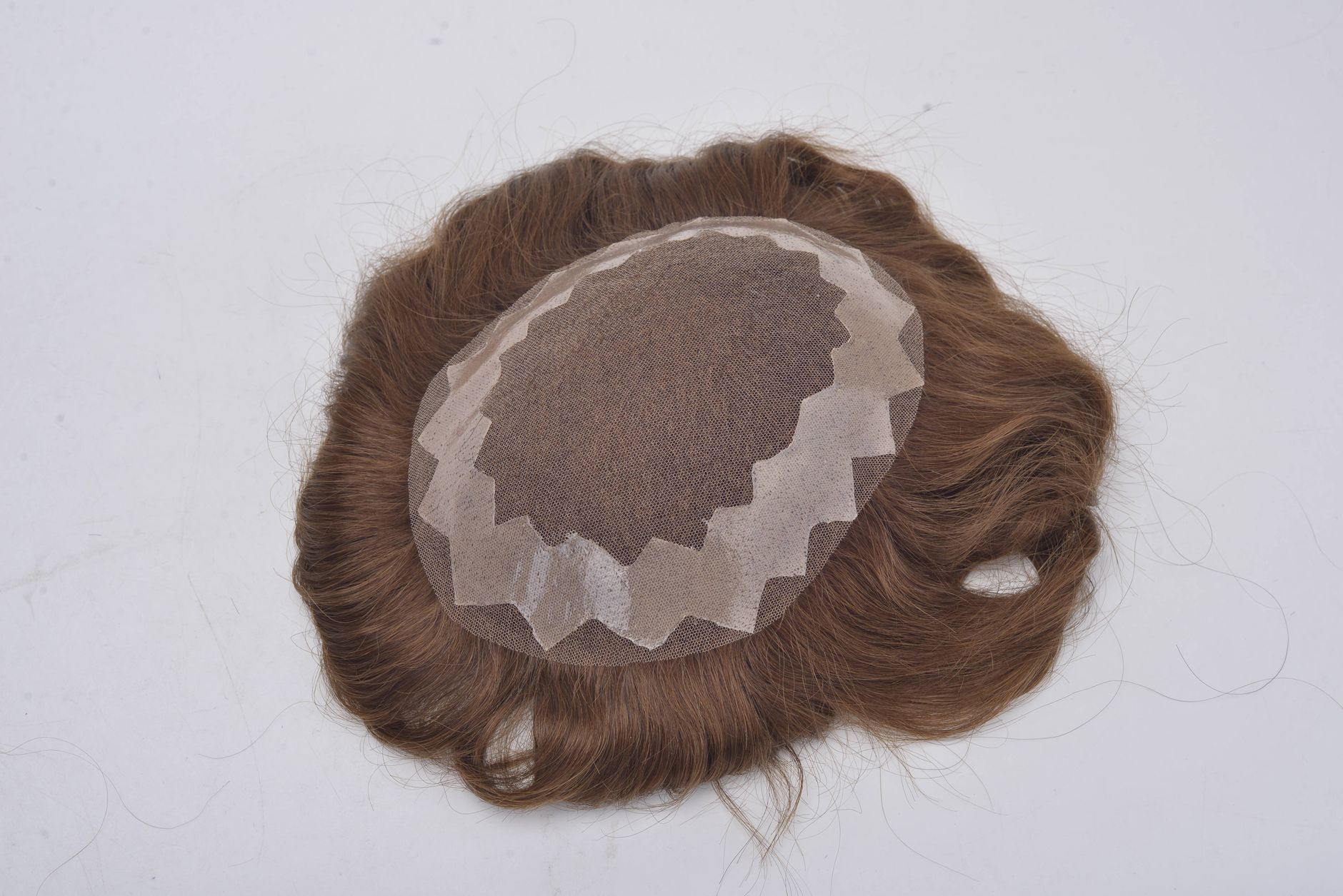 Close-up image of a brown hair wig on a white surface, showcasing texture and detail.