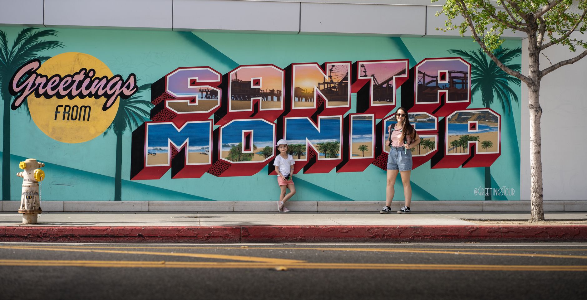Colorful street art mural in Santa Monica with people posing in front.