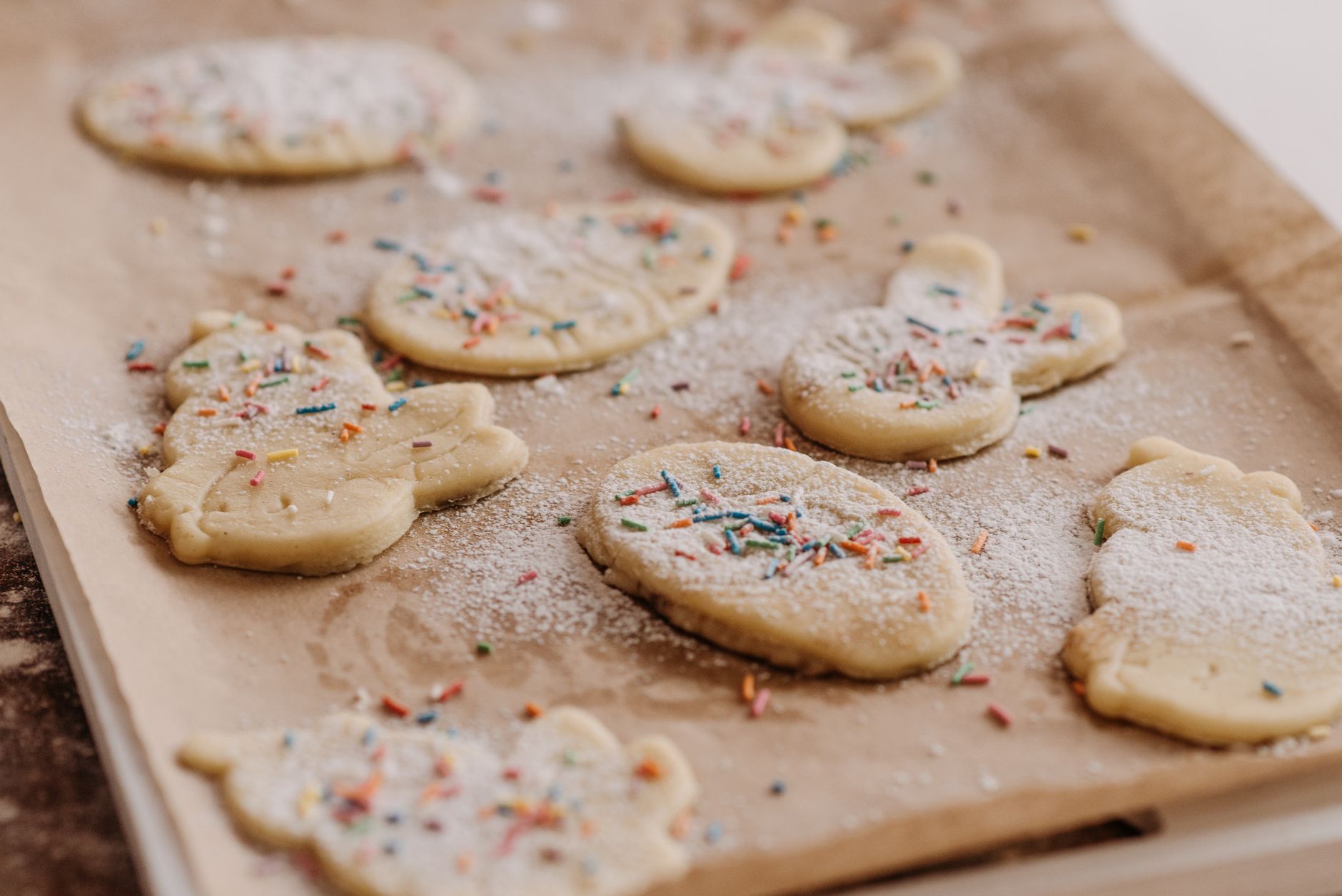 Close-up of raw cookies with sprinkles on baking parchment, ready to be baked.