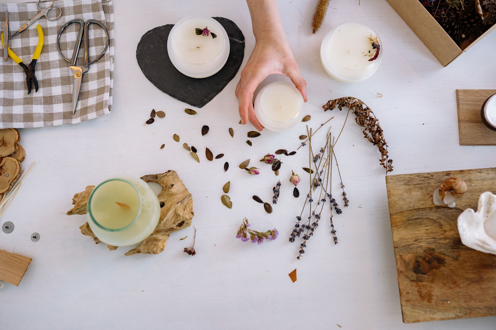 Artistic candle making setup with dried flowers and crafting tools.