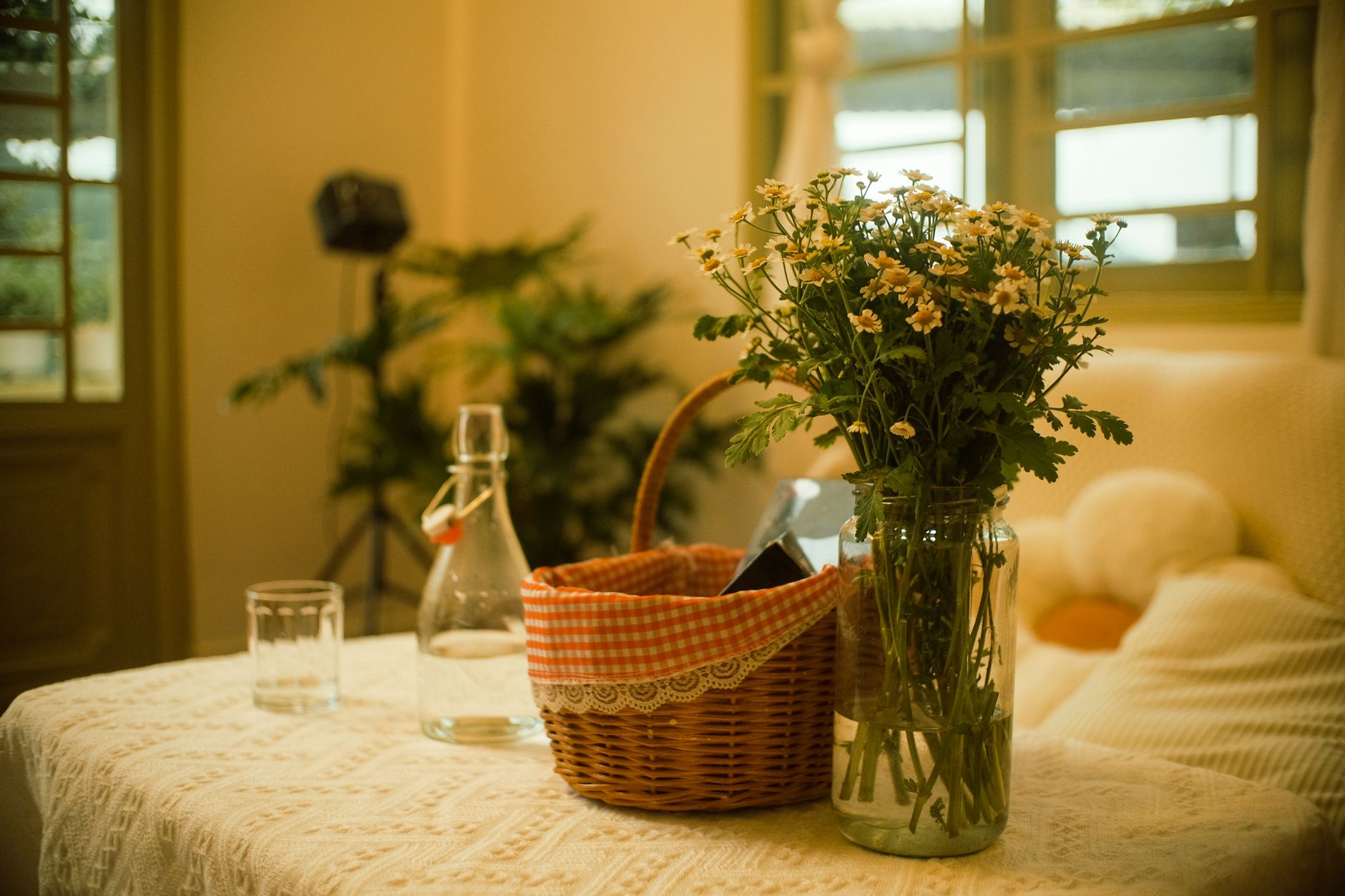Elegant indoor scene featuring a floral arrangement and picnic basket on a lace-covered table.