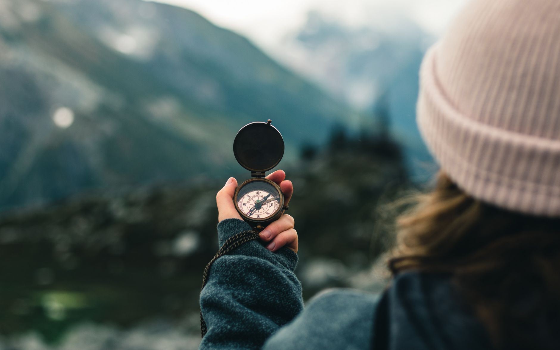 A woman holds a compass in the Canadian mountains, symbolizing adventure and exploration.