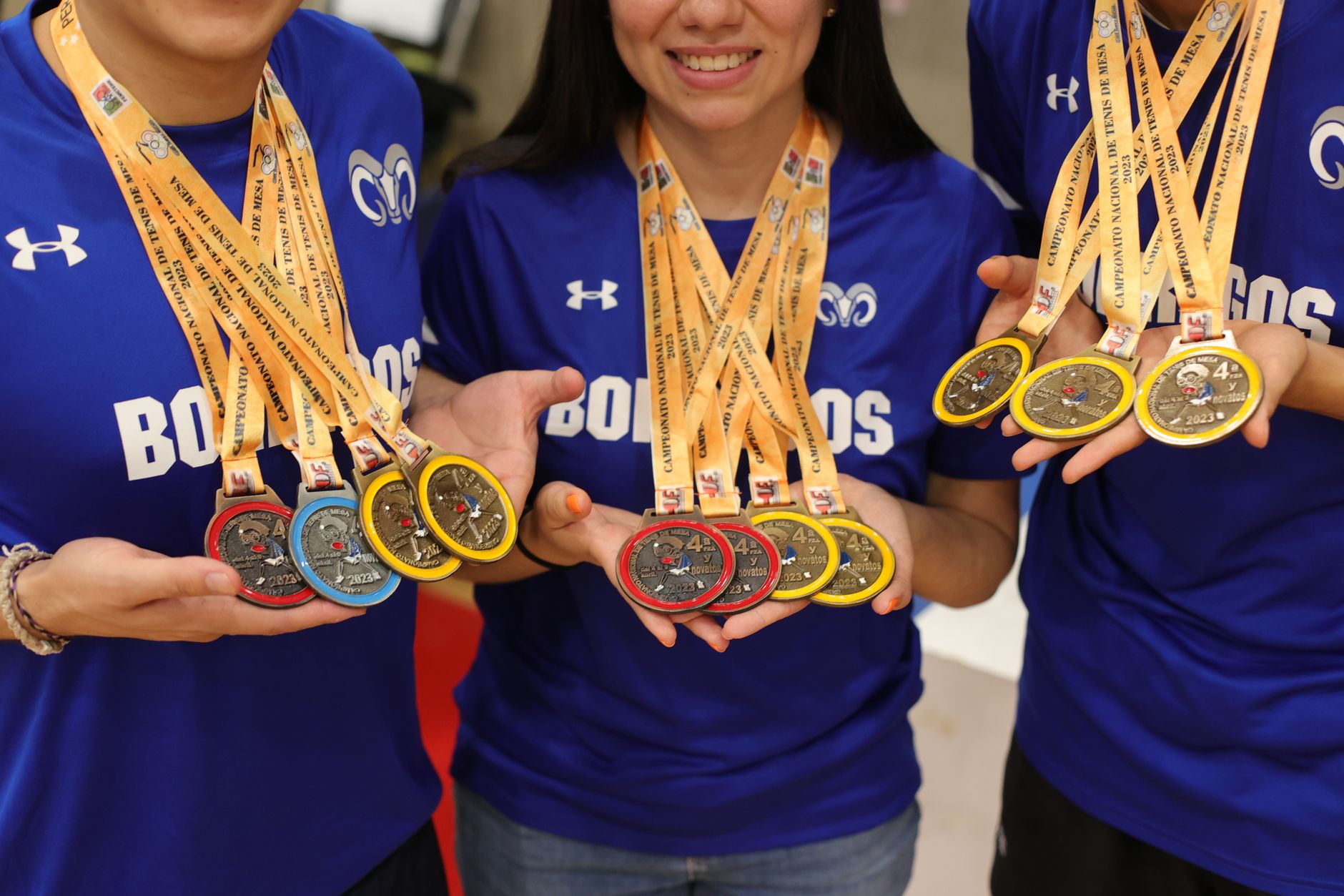 Group of athletes displaying their gold, silver, and bronze medals with pride and joy.
