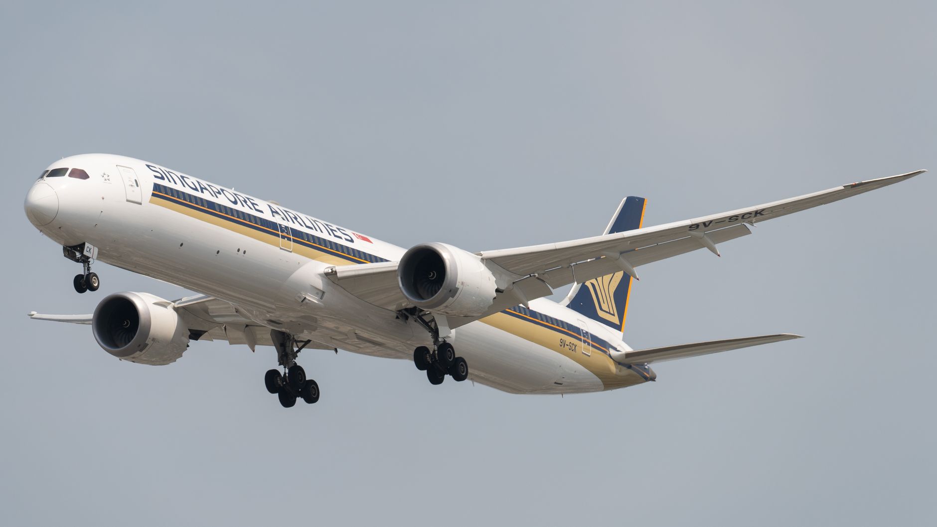 A Singapore Airlines Boeing 787-10 aircraft soaring through a clear sky.