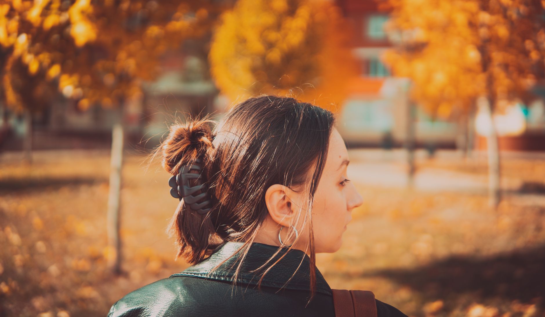 Woman in Vinnytsia park during fall, surrounded by colorful trees and leaves.