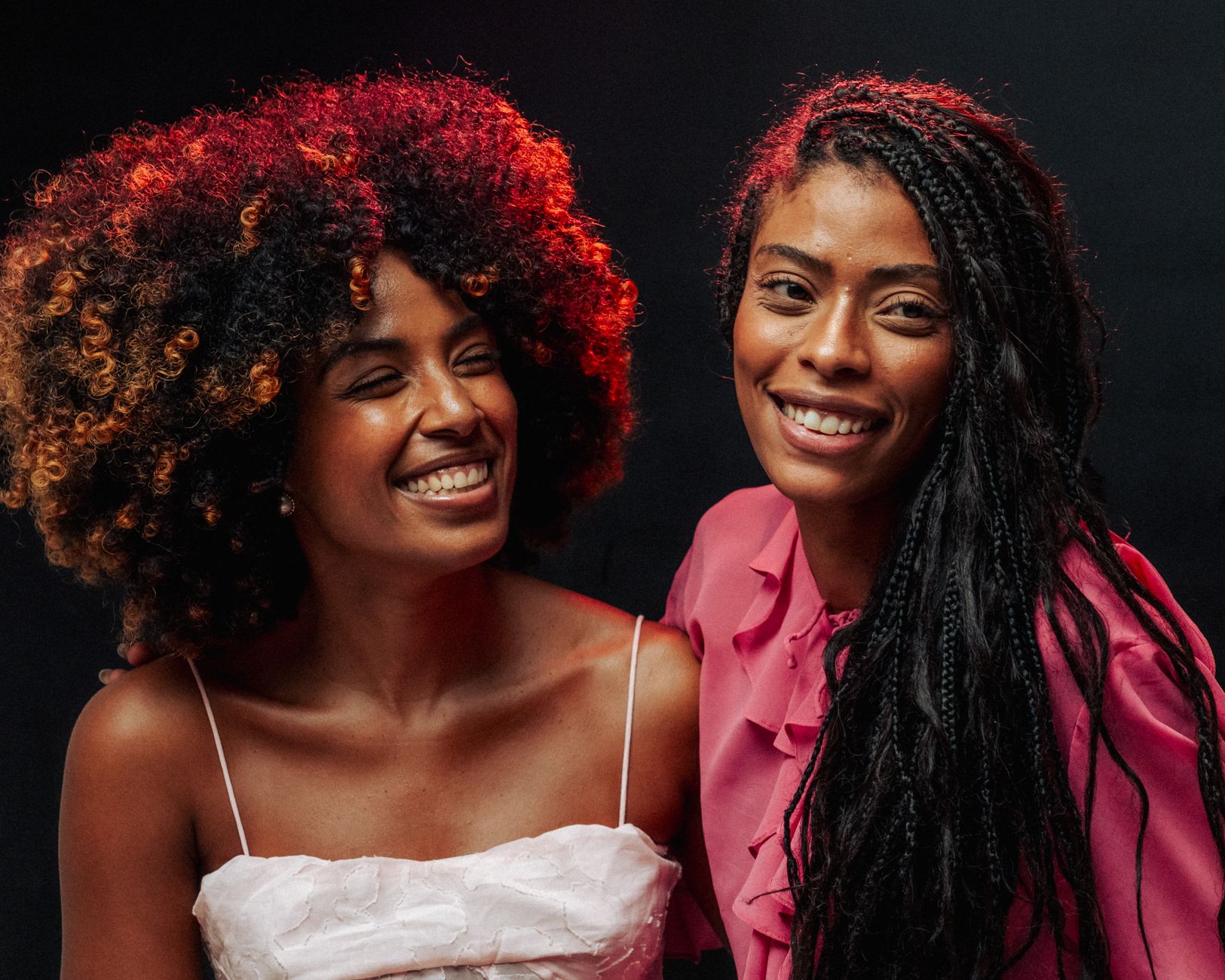 Two friends smiling warmly in vibrant attire, embodying joy and friendship.