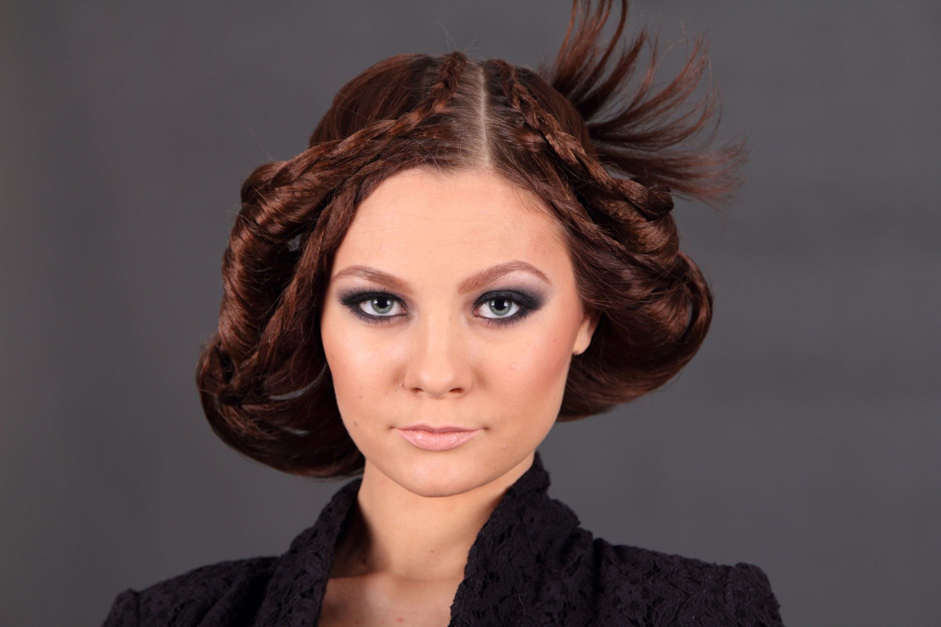 Elegant woman with braided hairstyle and dramatic makeup in studio portrait.