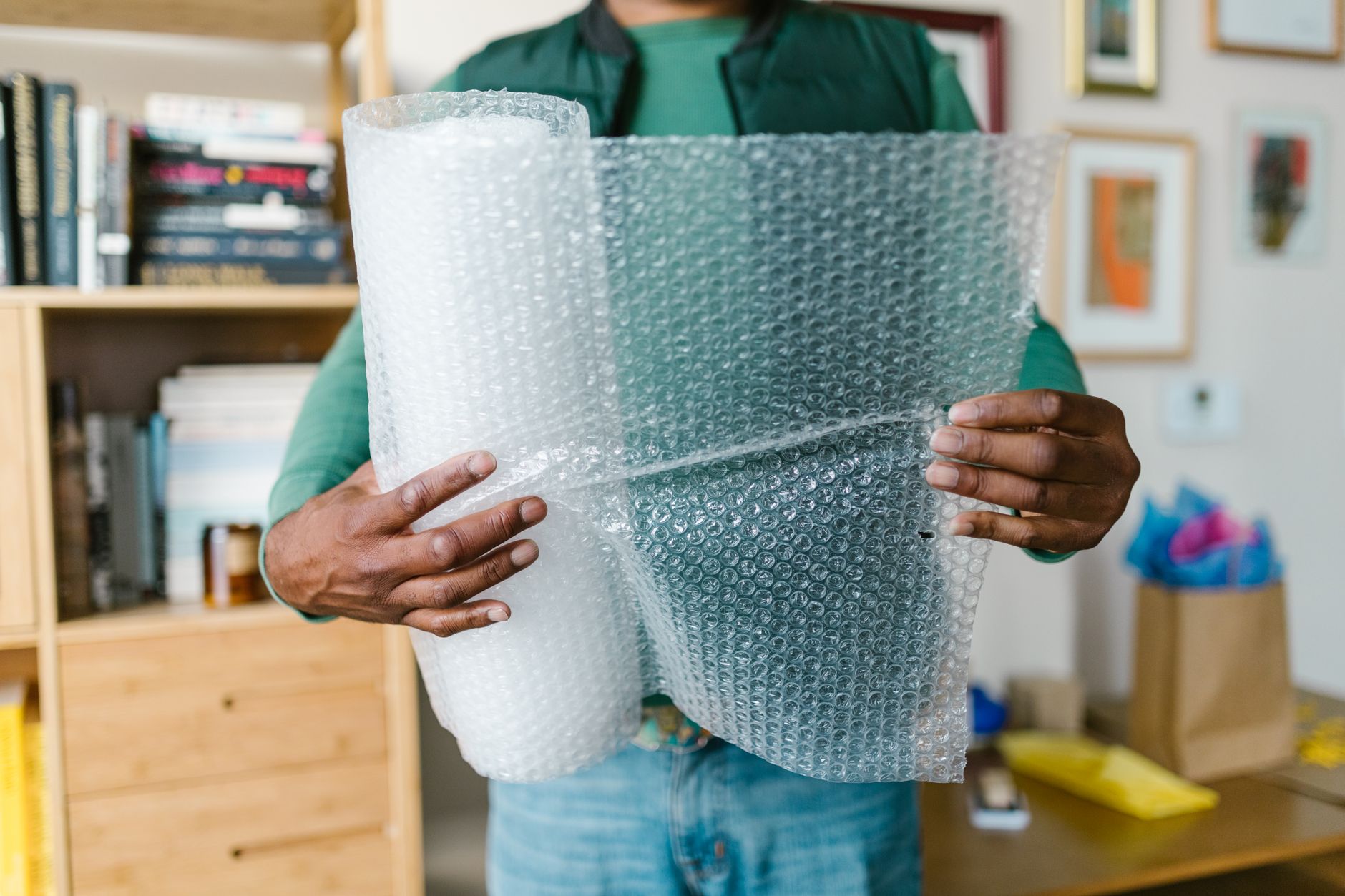 Close-up of hands holding bubble wrap at home. Ideal for packing or moving themes.