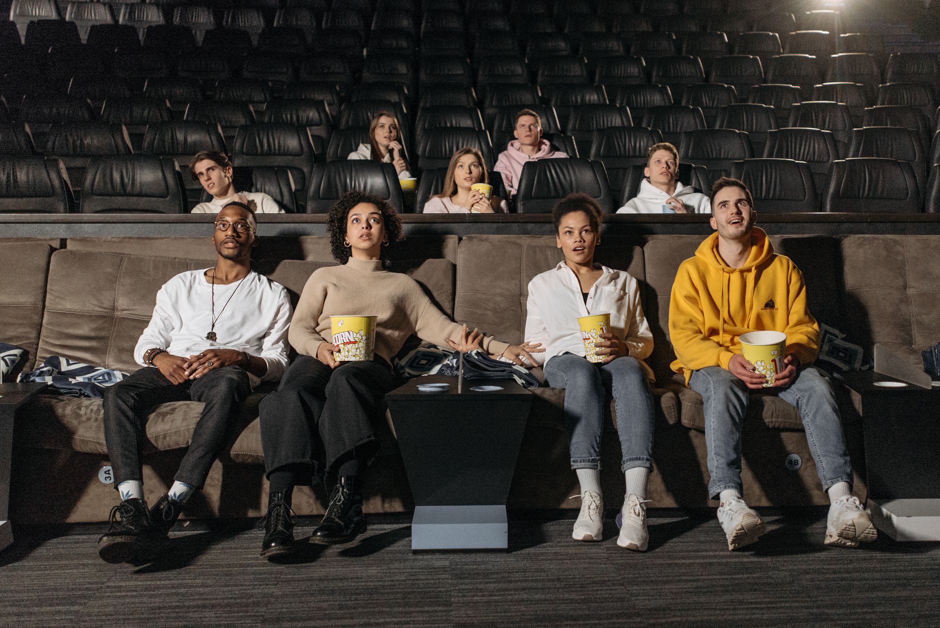A diverse group of people enjoying a suspenseful movie scene in a theater.