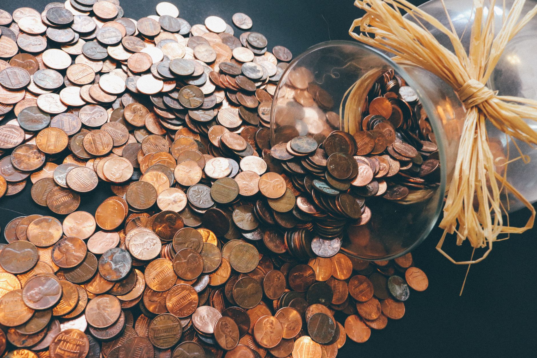 Spilled jar of pennies creating a pattern of coins representing savings and finance.