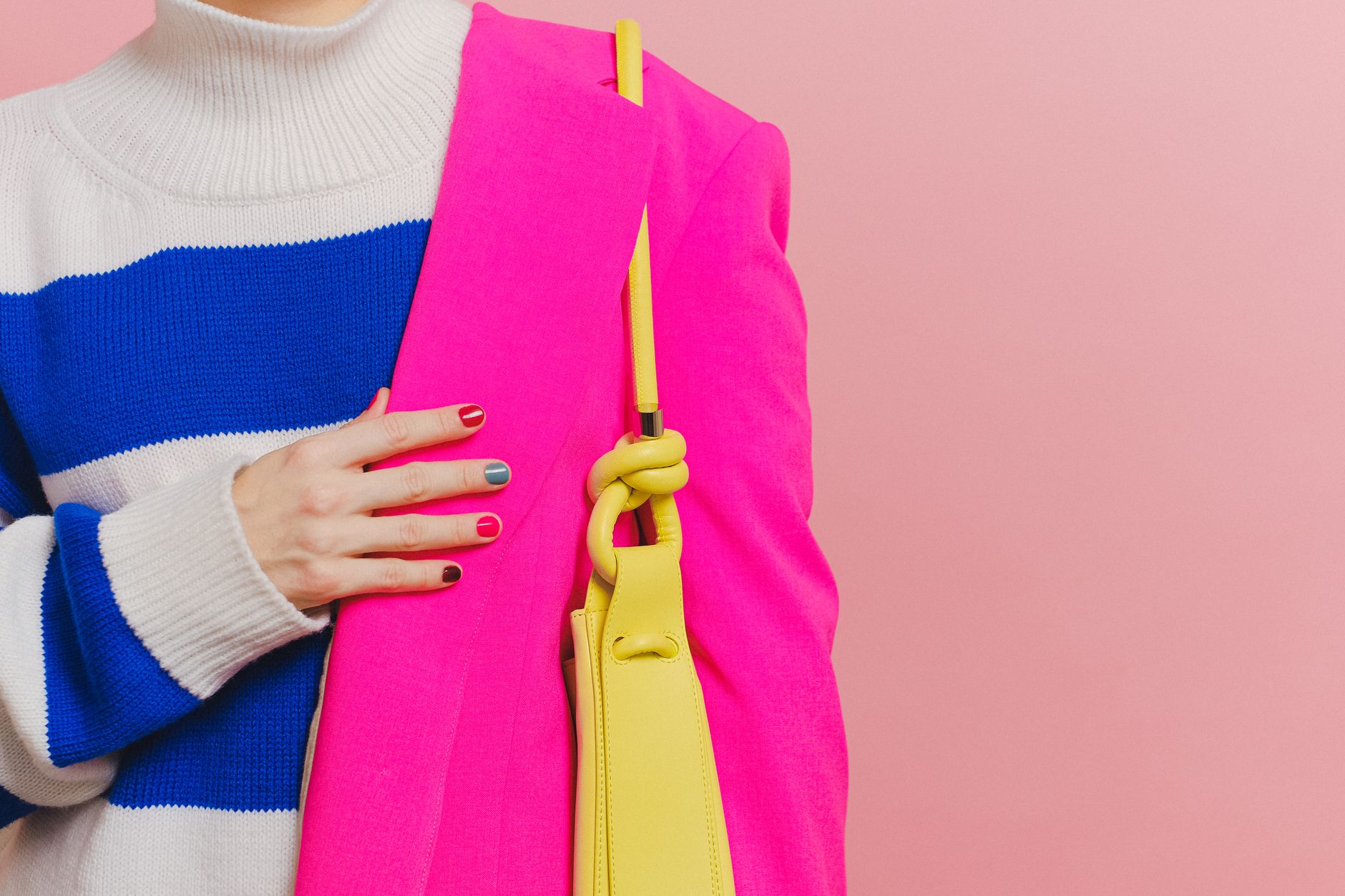 Vibrant image showcasing a stylish pink blazer paired with a yellow shoulder bag and colorful nails against a pink background.