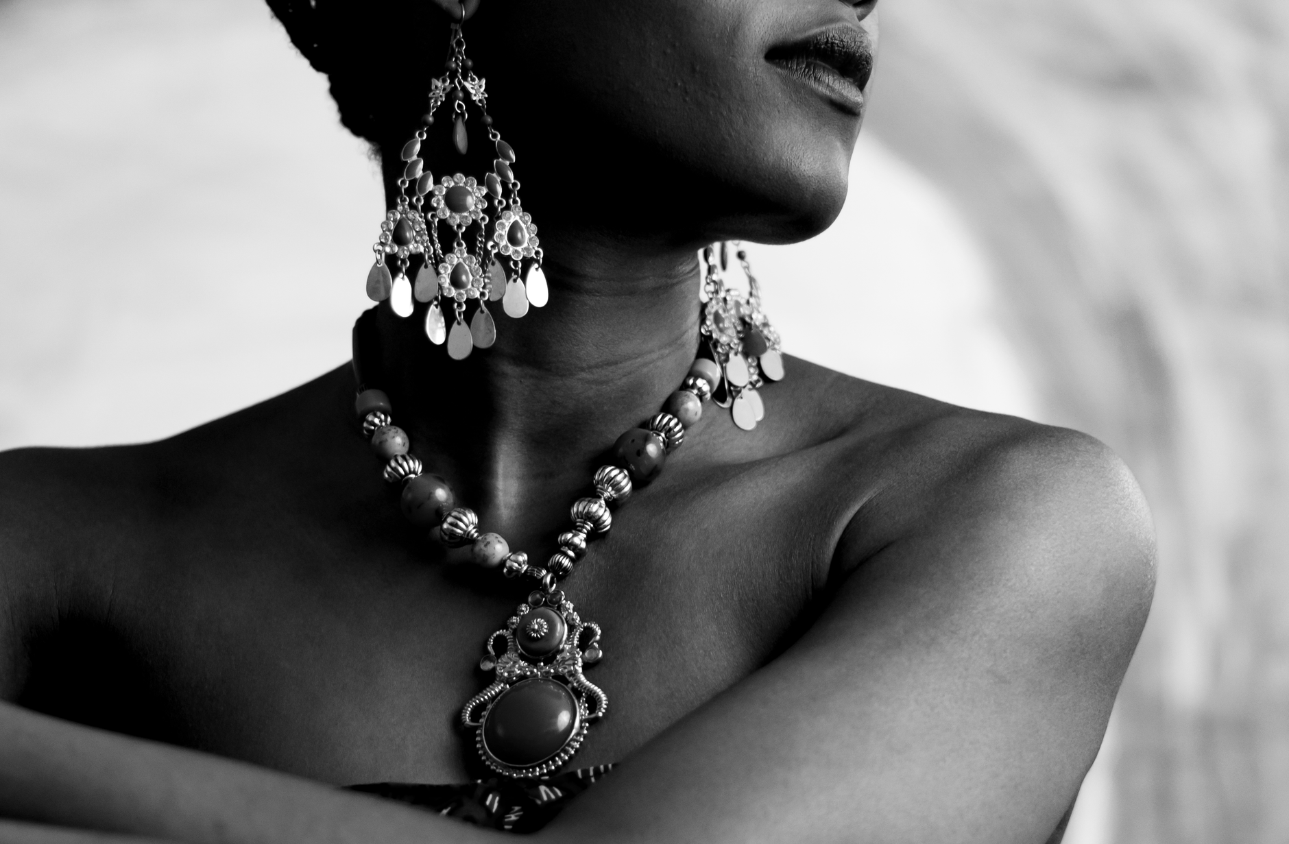 A stylish woman showcasing stunning earrings and a necklace in an artistic black and white portrait.