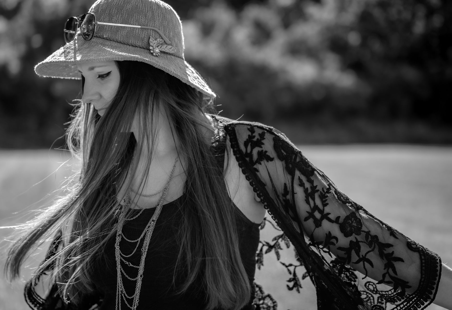 Fashionable woman with a sun hat and lace shawl enjoying a sunny day outdoors.