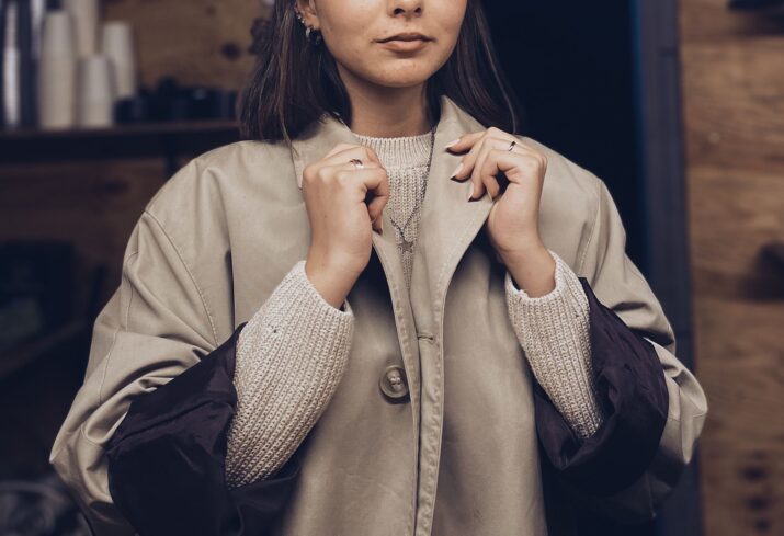 Stylish woman wearing a coat and sweater indoors, capturing a cozy fall fashion vibe.