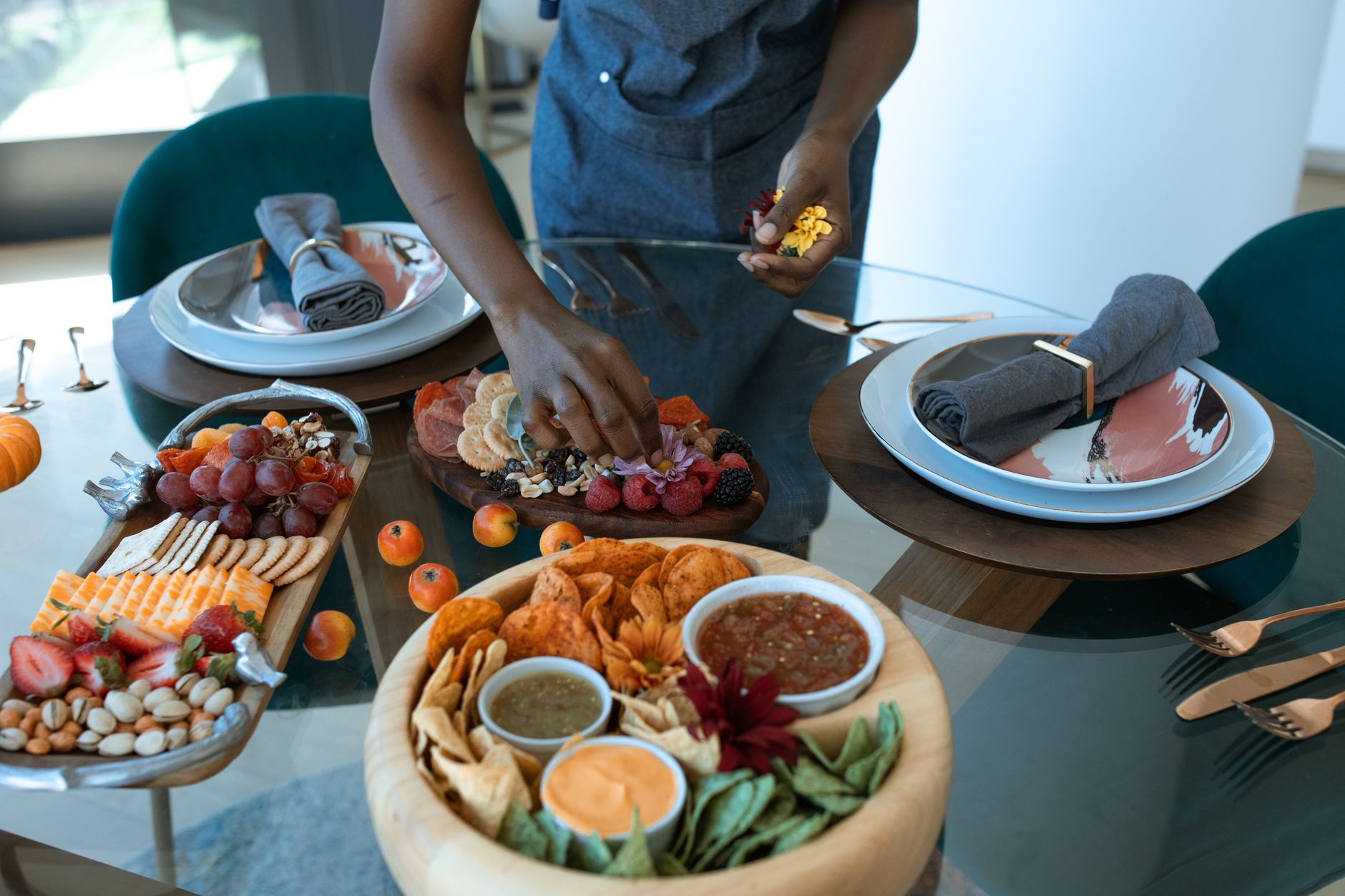 A beautifully arranged grazing table with various fruits, cheeses, and dips on a glass table setting.