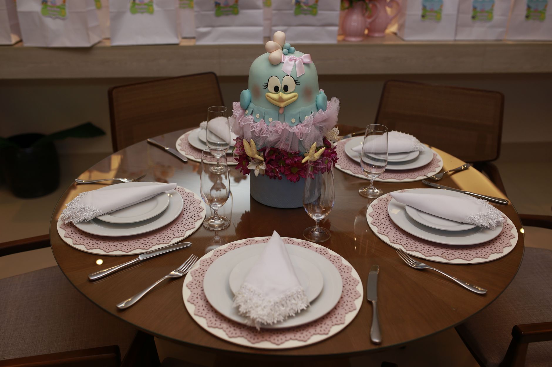 An elegant table setup featuring cutlery, plates, glasses, and a floral centerpiece with a cartoon toy bird.