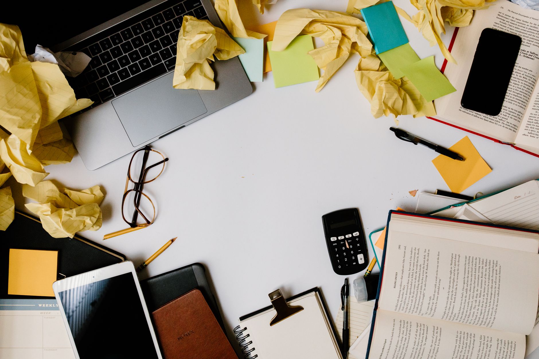 Top view of a messy office desk with electronics, books, and scattered notes, ideal for showcasing productivity chaos.