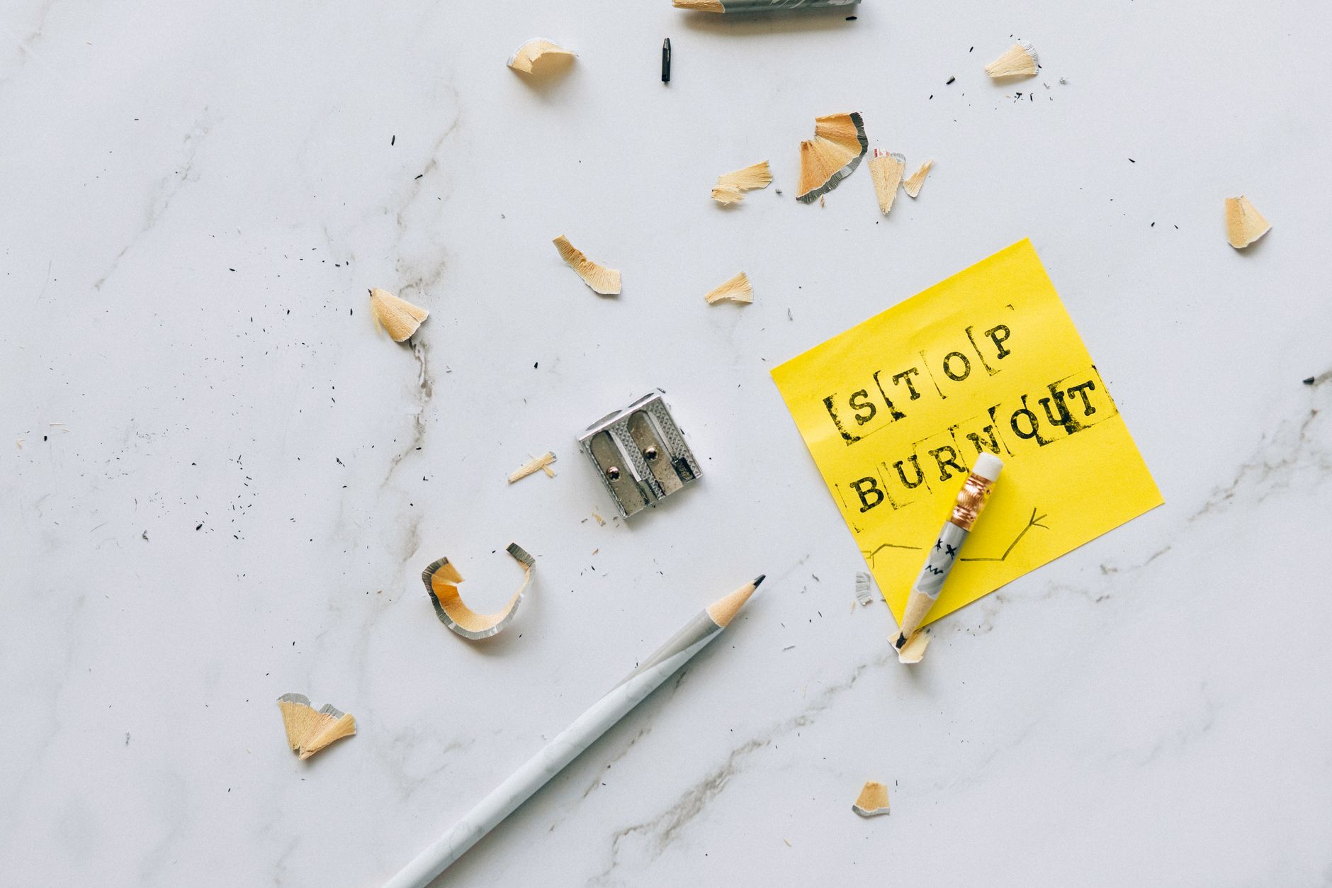 Overhead shot of a note saying 'Stop Burnout' on a marble surface with pencil shavings.
