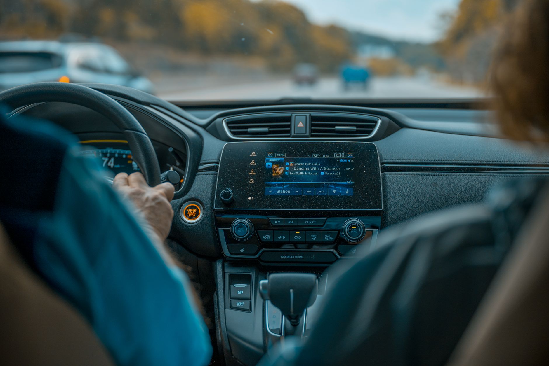 View from inside a car focusing on the dashboard, steering wheel, and road ahead.