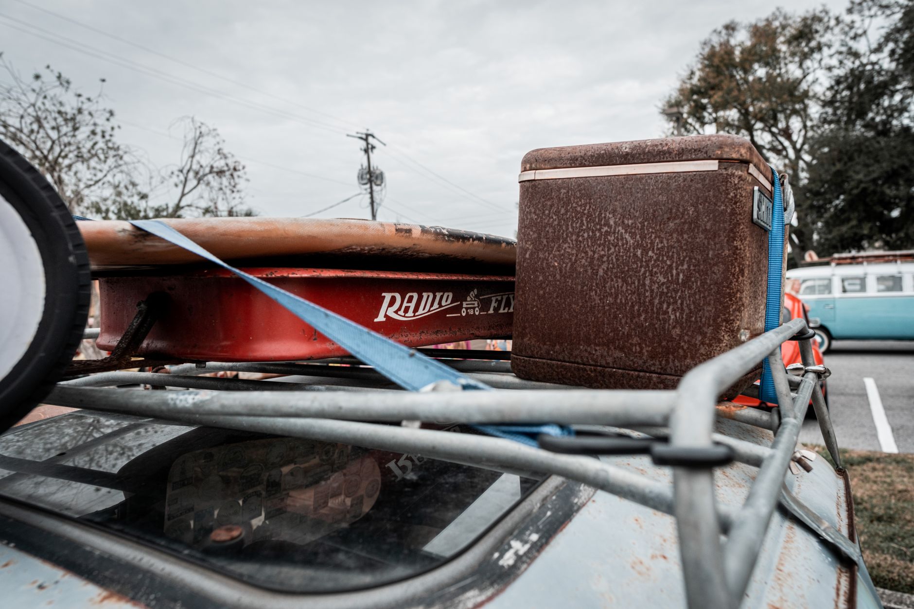 Old-fashioned Radio Flyer wagon and cooler on car roof, nostalgic road trip vibe.