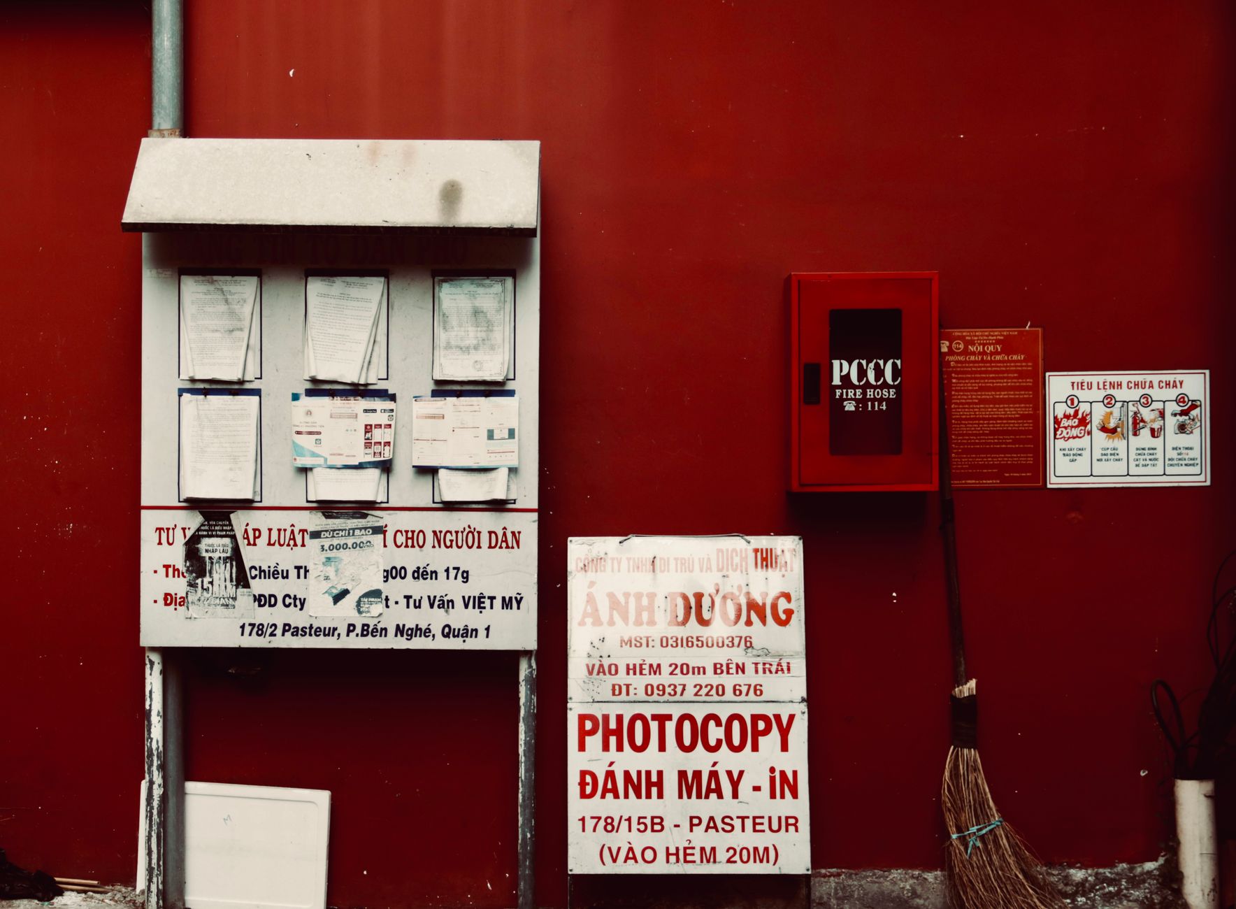 City environment with notices and fire hose on a vibrant red wall.