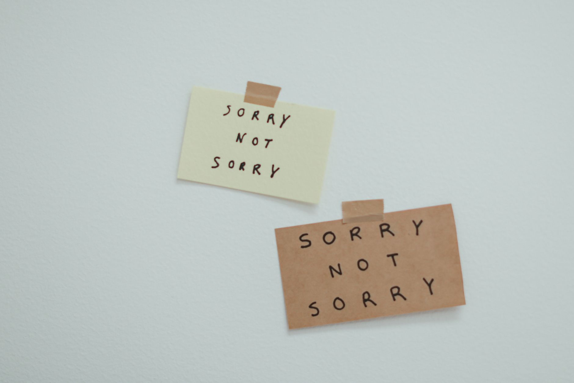 Two notes reading 'Sorry Not Sorry' taped to a wall, conveying a playful message.