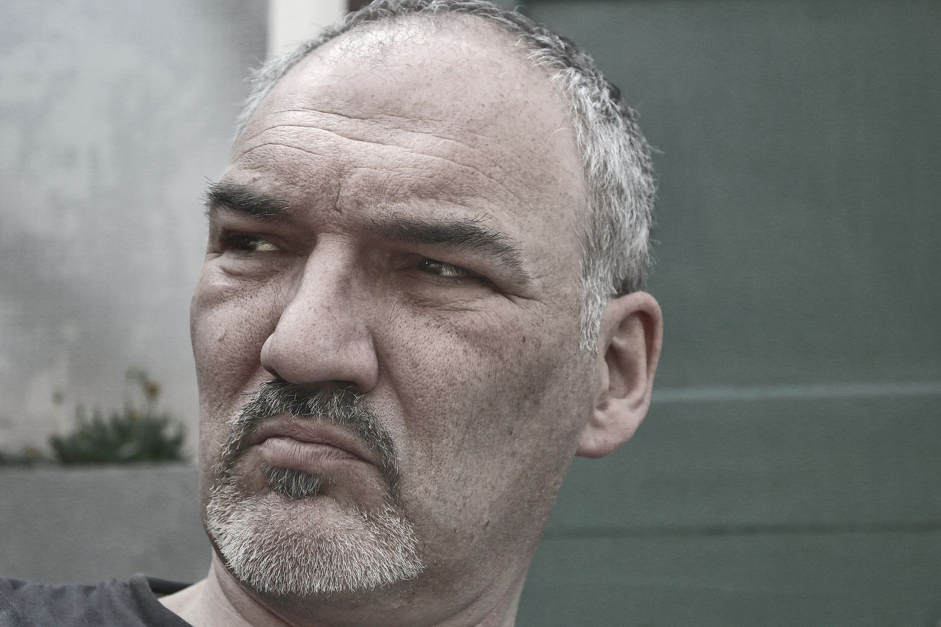 Close-up portrait of a thoughtful mature man with grey hair outdoors.