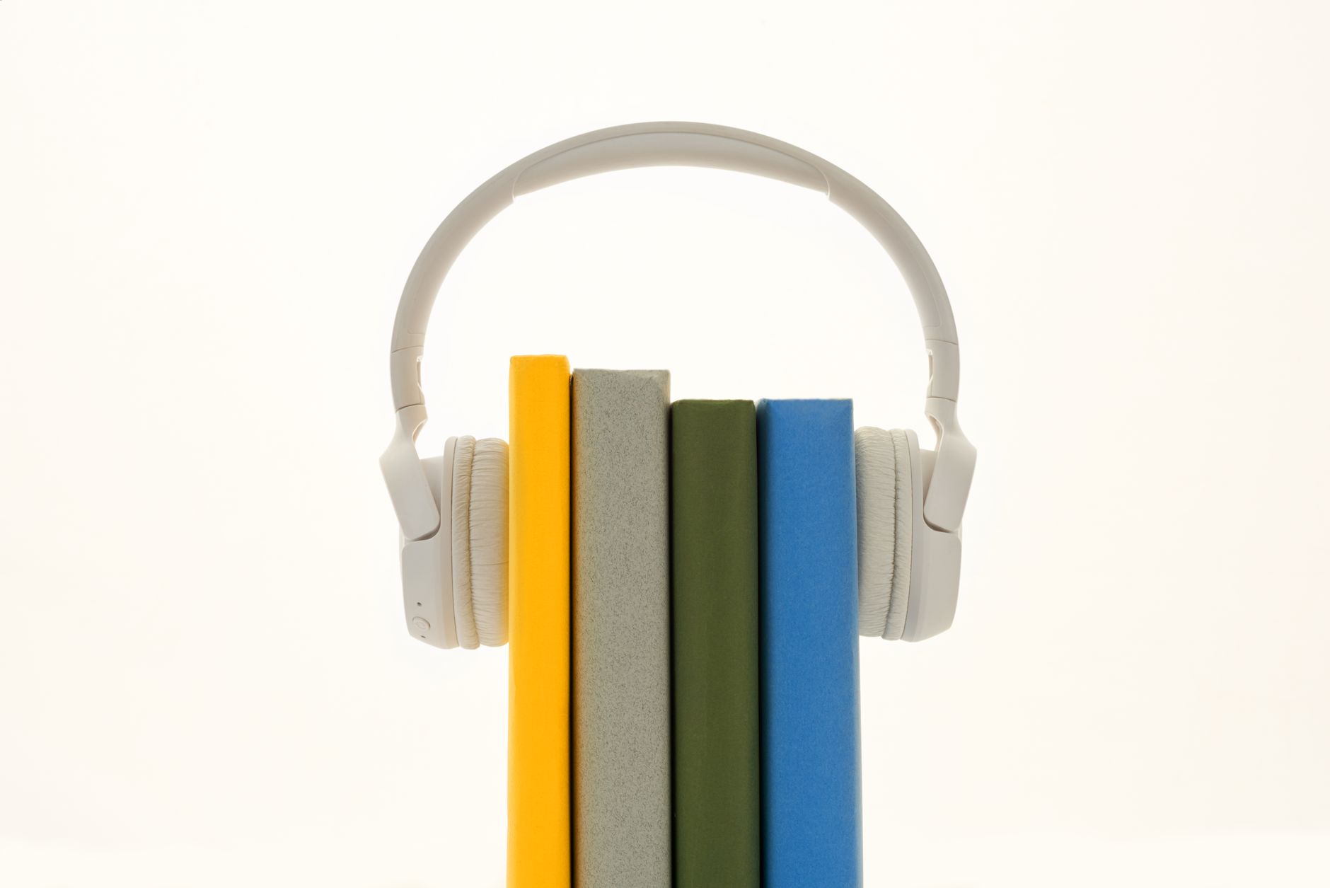 White headphones resting on colorful books, symbolizing modern audio technology.